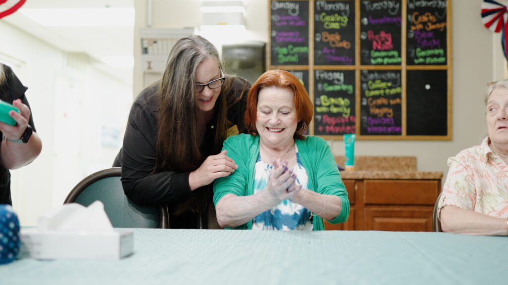A nurse and resident in front of an activity board at a skilled nursing facility, offering rewarding careers in healthcare