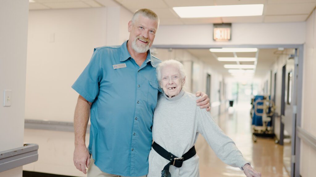 A nurse and resident hugging at smiling at a skilled nursing care facility