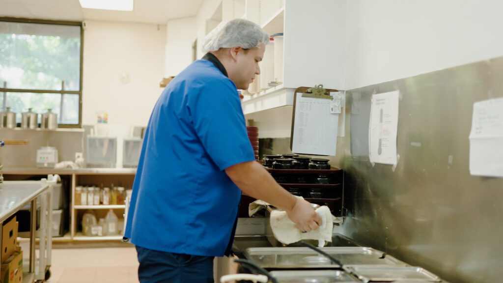 A kitchen staff worker preparing a meal for a skilled nursing facility