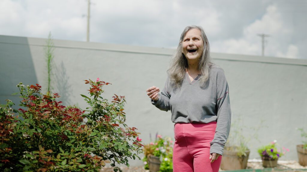 A woman smiles as she gardens in a respite care facility